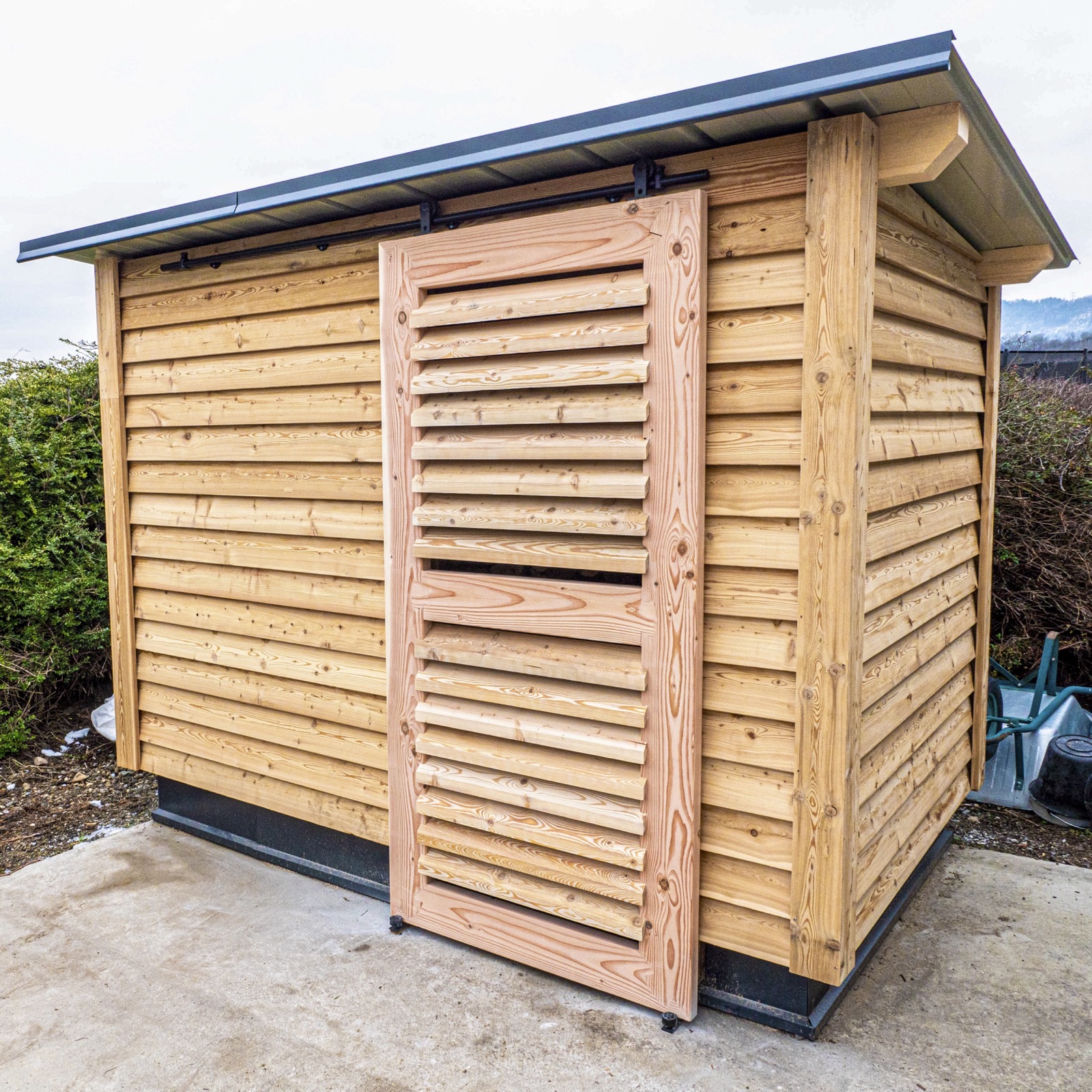 Cabane de jardin en bois avec bardage horizontal et porte à lames