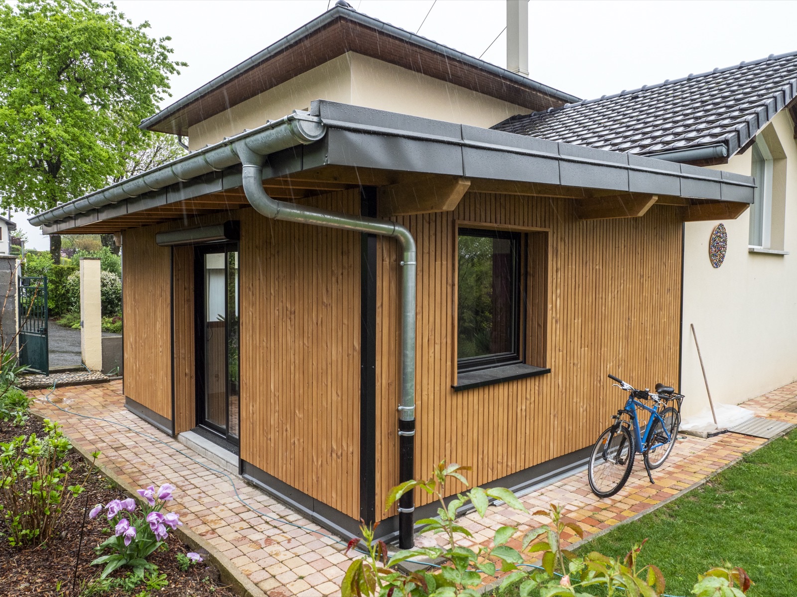 Extension ossature bois avec bardage vertical et descente d'eau pluviale zinc